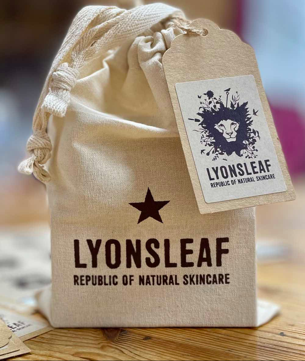 Beige drawstring bag with Lyonsleaf skincare branding on a wooden surface.